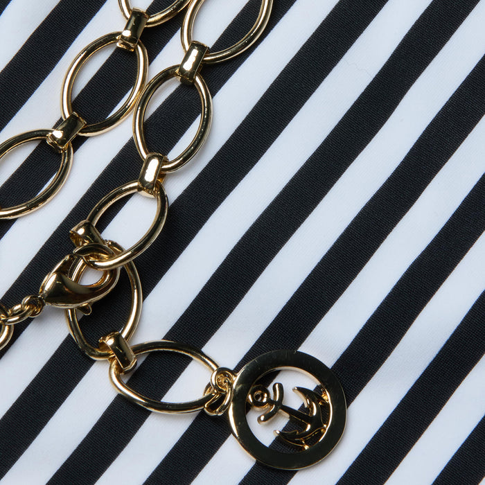 The Nicole Bikini Bottom is displayed on a black and white striped fabric background, exuding Parisian glamour.