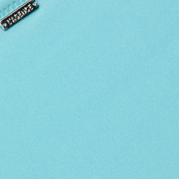 Close-up of a silver metallic tag with embossed design on the Nicole Bikini Bottom in ice blue. The tag is positioned near the top left corner, highlighting the smooth texture of the stretch nylon fabric.