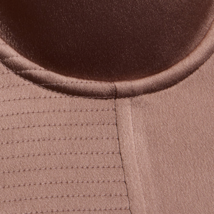 Close-up of a brown fabric with a circular seam at the top and parallel stitched lines on the left, showing texture and stitching details from the Nysa Bustier Top.