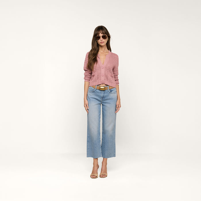 A person wearing the Orla Pointelle Knit Cardigan in mauve, paired with light blue cropped jeans, tan heels, and sunglasses stands against a plain white background.