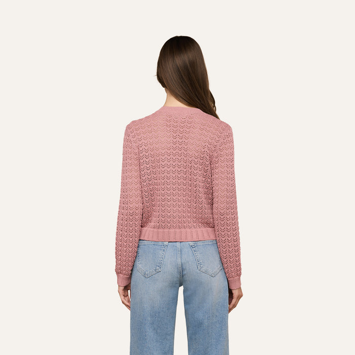 A woman with long brown hair, seen from behind, wears the Orla Pointelle Knit Cardigan in mauve and light blue jeans against a plain, light background.