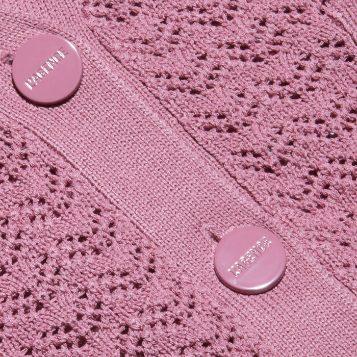 Close-up of the Orla Pointelle Knit Cardigan in mauve, showcasing its delicate lace-patterned pointelle knit fabric and two round pink buttons engraved with partially readable text. The lighting accentuates the airy texture of this lightweight beach cover up.