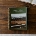 Peaks and Valleys Mens Spiral Study Cover on a brown wooden table next to an open book