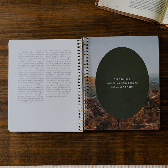Peaks and Valleys Mens Spiral Study opened to a short devotional page on a brown wooden table next to an open book