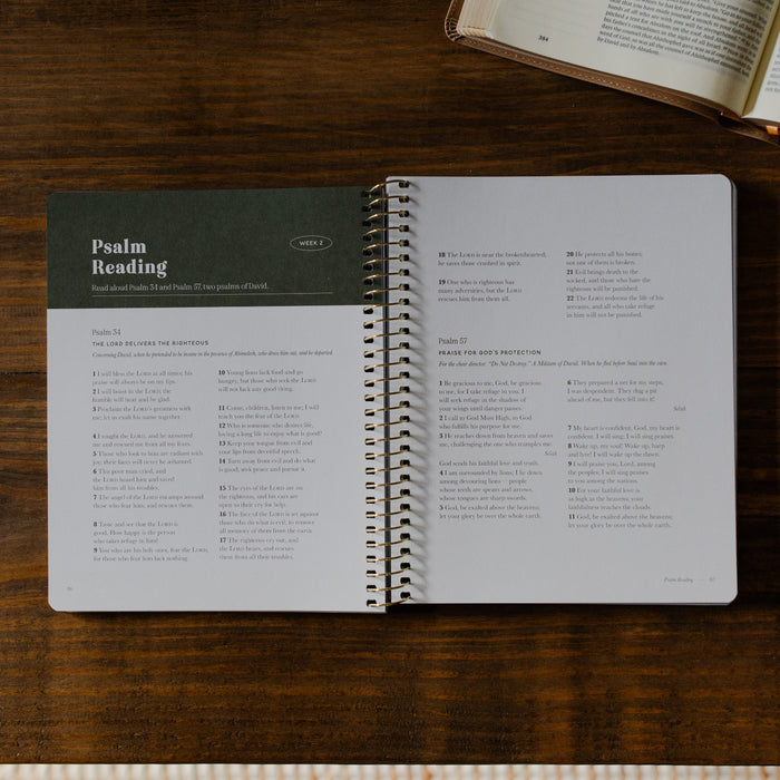 Peaks and Valleys Mens Spiral Study opened to a Psalm reading page on a brown wooden table next to an open book