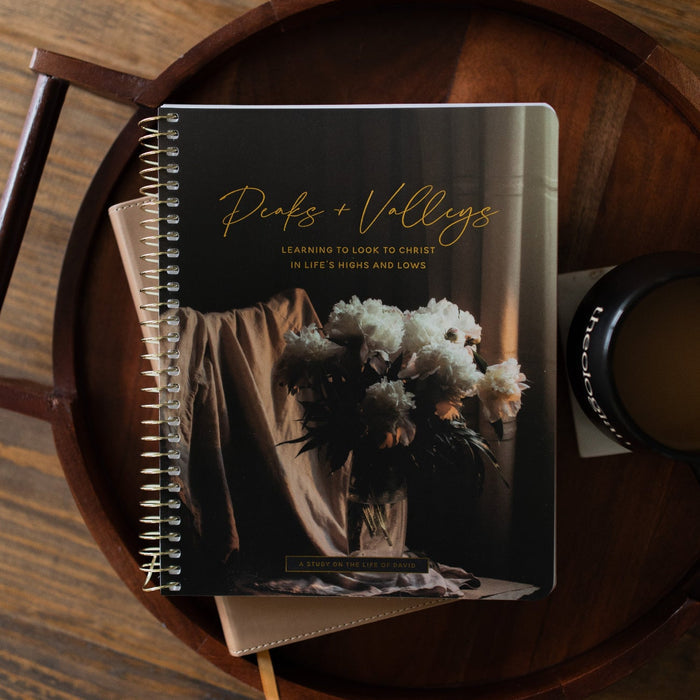 Peaks and Valleys Spiral Study on a dark brown wooden tray with a black coffee cup next to it on a brown wooden table