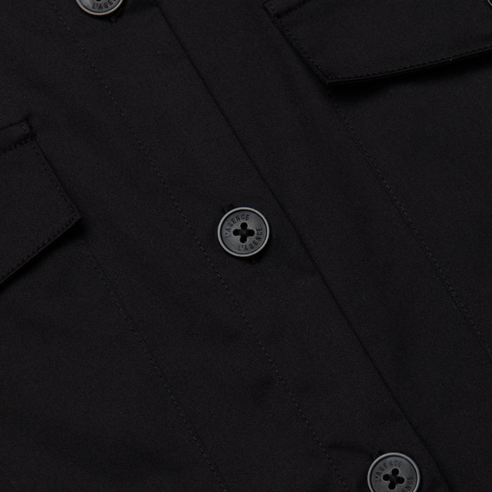 Close-up of the Pearson Poplin Shirt in black, featuring three round buttons and two flap pockets on either side.