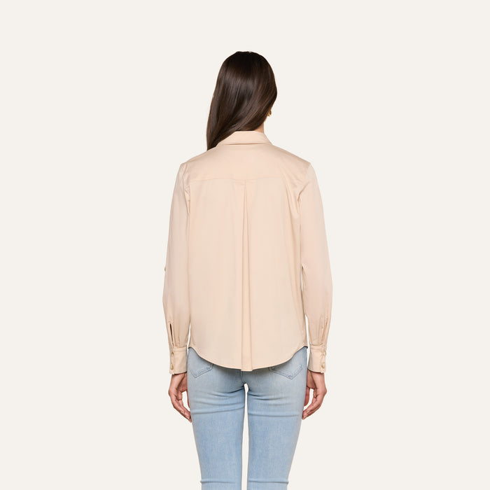 A person with long brown hair is shown from the back, wearing the Pearson Poplin Shirt—a beige utility-inspired button-down—and light blue jeans, standing against a plain white background.