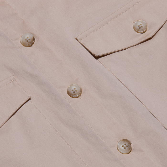 Close-up of the Pearson Poplin Shirt in light beige, featuring large buttons and two angled flap pockets, with a focus on the utility-inspired design, fabric texture, and detailed stitching.