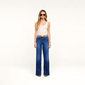 A woman models the Petite Scottie Wide-Leg Jean, paired with sunglasses and a cream tank top, standing facing forward in a neutral, well-lit studio with a plain background.