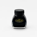 A front-facing image of the Platinum Carbon Ink bottle. The label is fully visible, featuring the "Carbon Ink" logo in gold lettering against a black background. The glass bottle has a distinctive shape, and the deep black ink inside is prominently displayed.