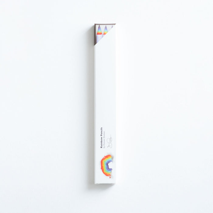 Rainbow pencils in the box on a white desk showing the rainbow coloured wood