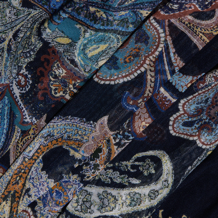The Rasha Shirred Mesh Tank features a dark fabric adorned with an intricate paisley pattern in blue, teal, orange, and cream, highlighting swirling shapes and floral details. Designed with a square neckline for versatility, this women’s top showcases elegantly folded mesh that creates overlapping sections and textured dimension.