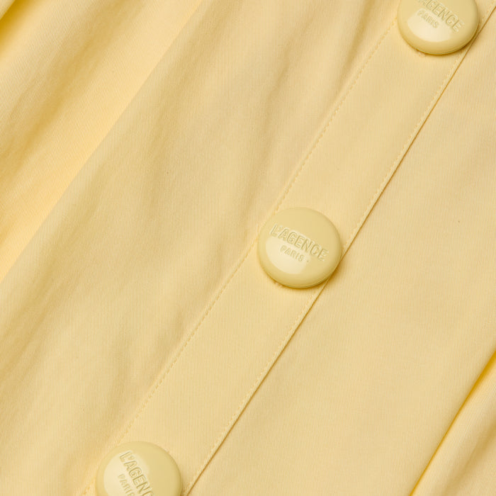 Close-up of the Reanne Midi Dress in yellow poplin, featuring matching buttons embossed with the words LAGENCE PARIS. The image highlights the fabric’s texture and detailed button design.