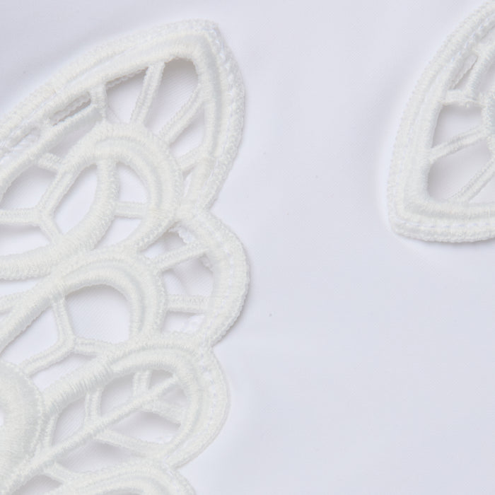 Close-up of the Remi One-Piece Swimsuit, showcasing intricate white lace embroidery with curved patterns, open spaces, and delicate butterfly appliqué details against a plain white background.