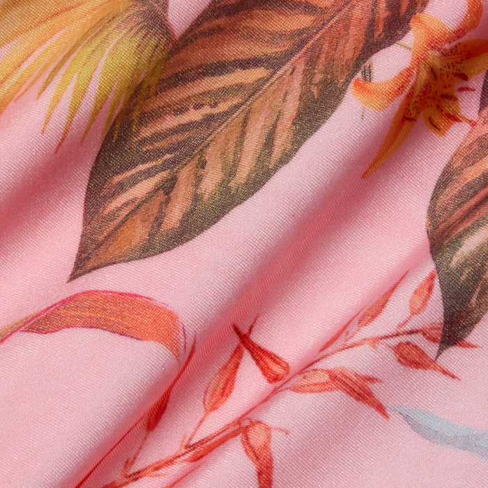 The Remi One-Piece Swimsuit features pink fabric adorned with a detailed tropical floral and palm leaf print in brown, orange, and yellow hues. The softly crinkled material enhances the texture and vibrant botanical pattern—ideal for crafting an eye-catching one-piece or high-leg swimsuit.