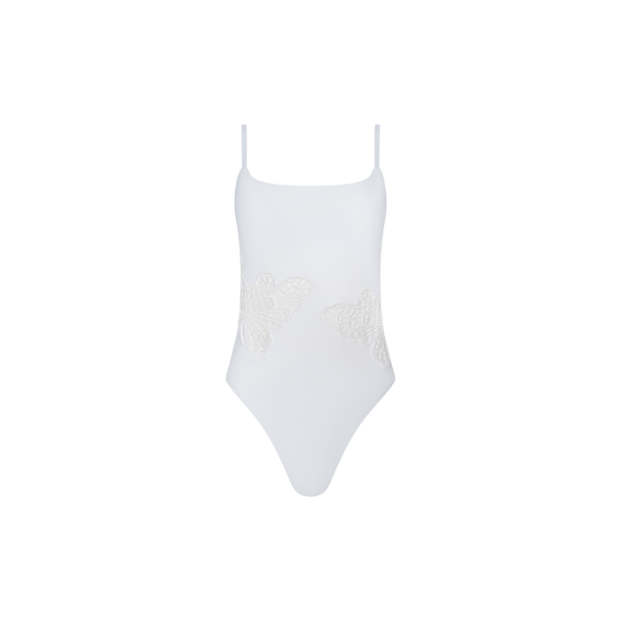 The Remi One-Piece Swimsuit is a white swimsuit with thin shoulder straps, a high-leg cut, and two lace butterfly appliqués on the front sides, displayed against a plain white background.