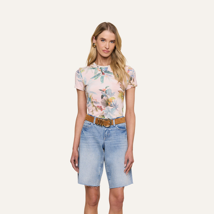 Woman standing against a white background, wearing the Ressi Fitted Tee, light blue denim knee-length slim cut shorts, a brown belt, and earrings. She has long blonde hair and a neutral expression.