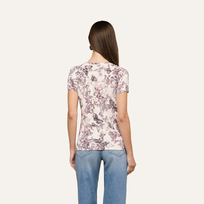 A woman with long brown hair is seen from behind, wearing the Ressi Fitted Tee and light blue jeans against a plain light background.