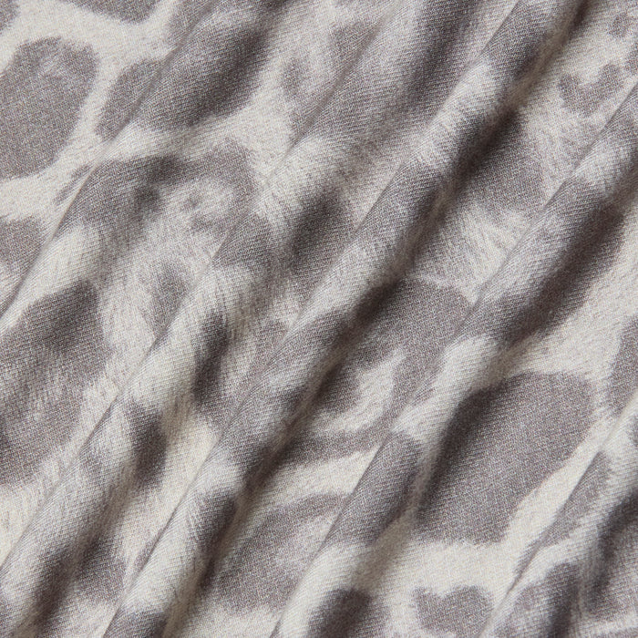 A close-up of the Ressi Fitted Tee showcases its stretch jersey knit fabric in a gray leopard print pattern, featuring soft folds and a slightly textured surface.