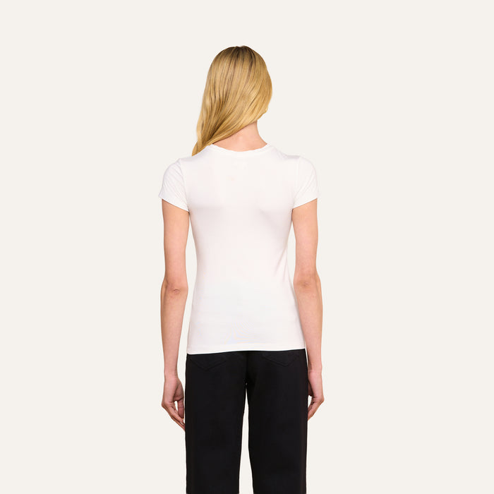 A person with long blonde hair, seen from behind, is wearing the form-fitting Ressi Fitted Tee in white and black pants, standing against a plain light background.