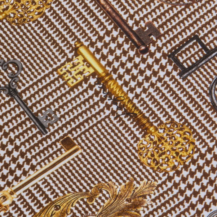 Several ornate vintage keys, both gold and black, are arranged diagonally on a textured brown houndstooth fabric background featuring the Ressi Fitted Tee.