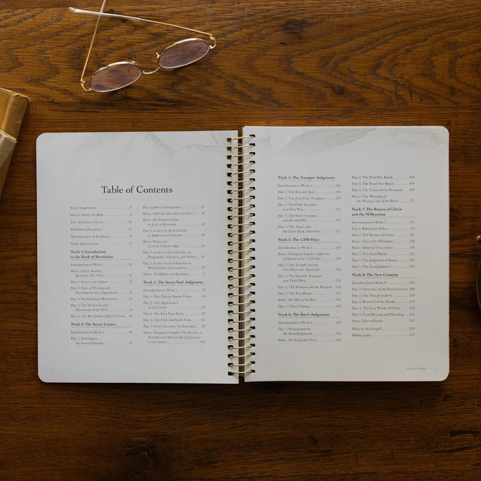 Revelation Spiral Study opened to the table of contents page on a wooden table next to a pair of glasses