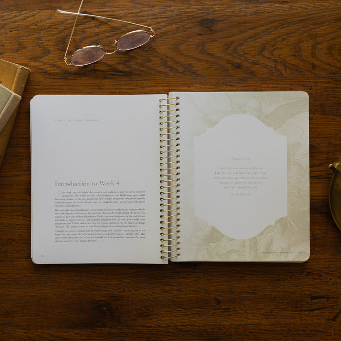 Revelation Spiral Study opened to page 104, introduction to Week 4, on a wooden table next to a pair of glasses