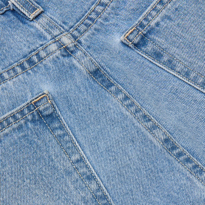 Close-up of the River Jean Bermuda Short in blue denim, highlighting the front pockets, seams, and textured fabric. The visible stitching and weave detail showcase the classic all-cotton jean construction.