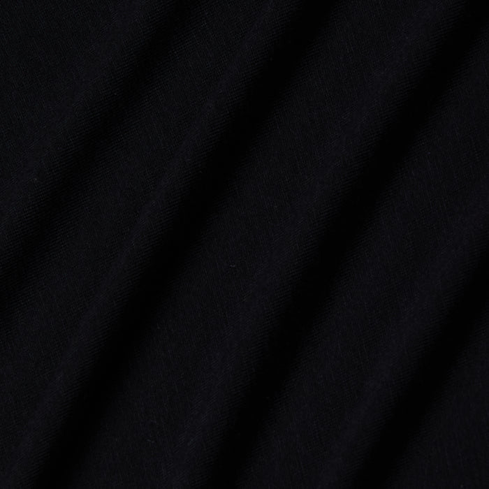 Close-up of black stretch jersey fabric with soft, diagonal folds creating gentle shadows and texture, highlighting the smooth and slightly matte surface characteristic of the Riza Boatneck Bodysuit.