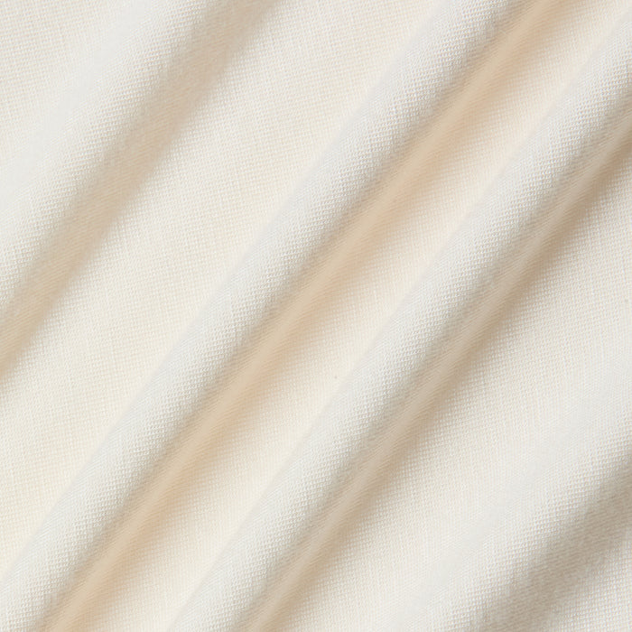 Cream-colored stretch jersey fabric with a soft, smooth texture, featured here in the Riza Boatneck Bodysuit, shown with gentle diagonal folds and subtle shadows that highlight the material’s weave and drape.