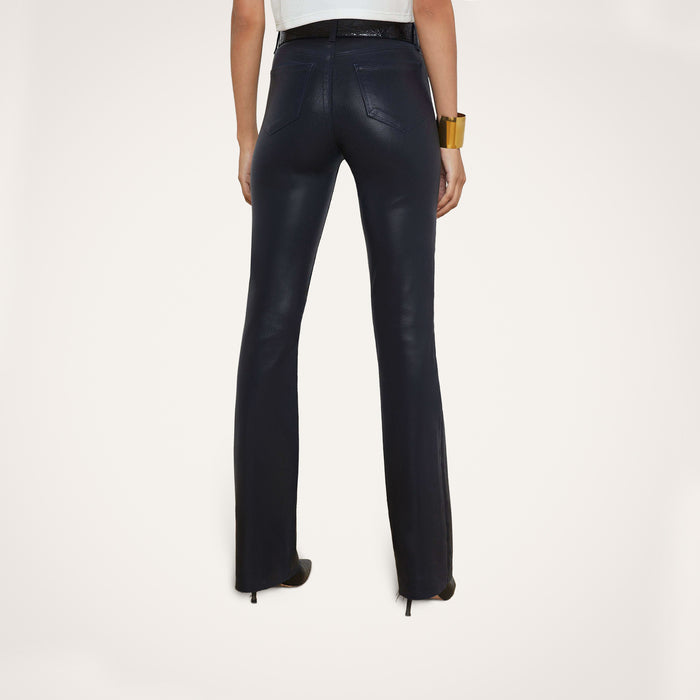 A person stands facing away against a plain white background, wearing the Ruth Coated Straight-Leg Jean in black, paired with black heels, a white top, and a large bracelet.