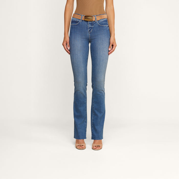 A person wearing Ruth Straight-Leg Jeans in indigo with a brown belt, a tan sleeveless top, and beige heeled sandals stands against a plain white background.