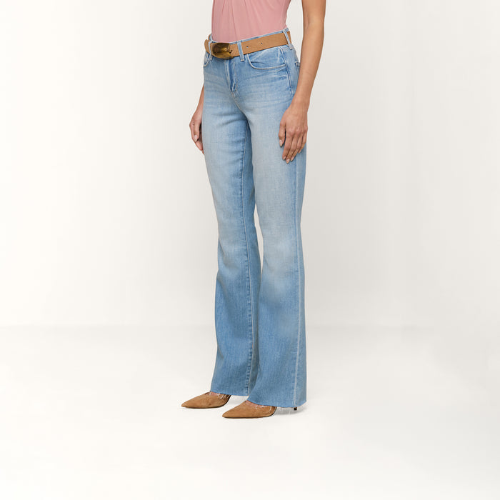 A person wearing the Ruth Straight-Leg Jean in a light indigo wash, styled with a brown belt, a pink top, and tan pointed-toe shoes, is standing against a plain white background.