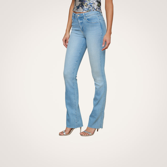 Wearing the Ruth Straight-Leg Jean in a light blue, vintage wash with slight fading, styled with a floral top and silver open-toe heels, a person stands against a plain white background.
