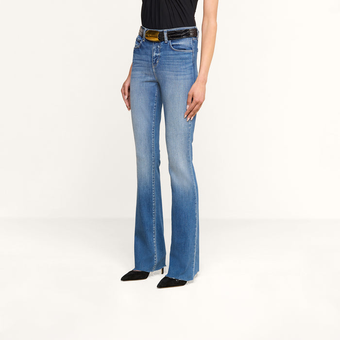 Person wearing Ruth Straight-Leg Jean in light blue, crafted from premium stretch denim. Paired with a black top, black belt, and black pointed shoes. The background is plain white, and only the lower half of the body is visible.