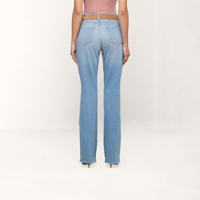 A person is shown from the back against a plain white background, wearing the Ruth Straight-Leg Jean in a light indigo wash with a raw hem and paired with a pink top.