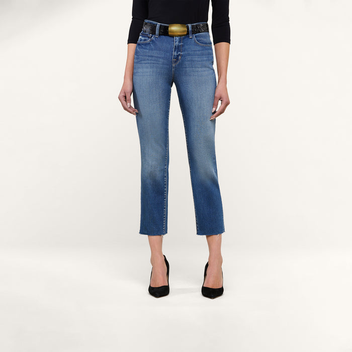 A person wearing the Sada Slim-Leg Cropped Jean, paired with black pointed heels, a black three-quarter sleeve top, and a wide belt stands against a plain white background.