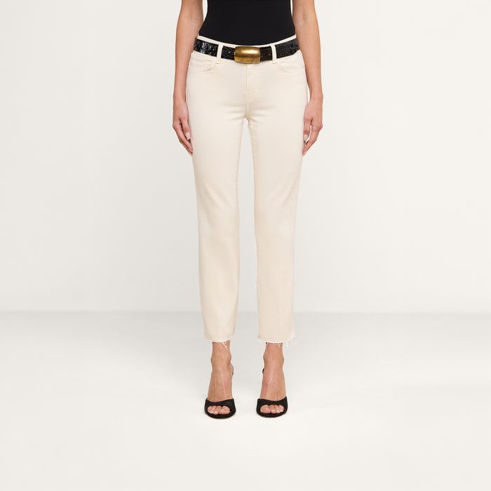 A person wearing a black top, Sada Slim-Leg Cropped Jeans in off-white with a black belt featuring a gold buckle, and black high-heeled shoes stands against a plain white background.