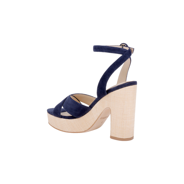 The Sandrine Platform Sandal in navy suede features a thick crisscross strap, an ankle strap, and a beige block heel and platform, shown against a white background.