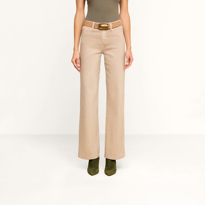 A person wearing the Scottie Coated Wide-Leg Jean in beige, styled with a brown belt, paired with a fitted olive sleeveless top and olive green boots, stands against a plain white background.