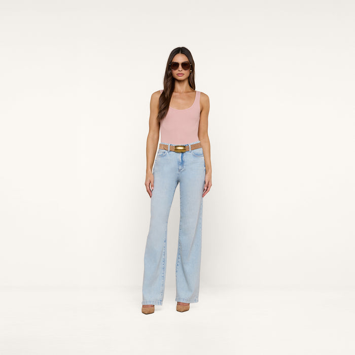 A woman stands against a plain white background wearing sunglasses, a pink tank top, brown shoes, and the Scottie Wide-Leg Jean in a light wash high-rise style with a belt.