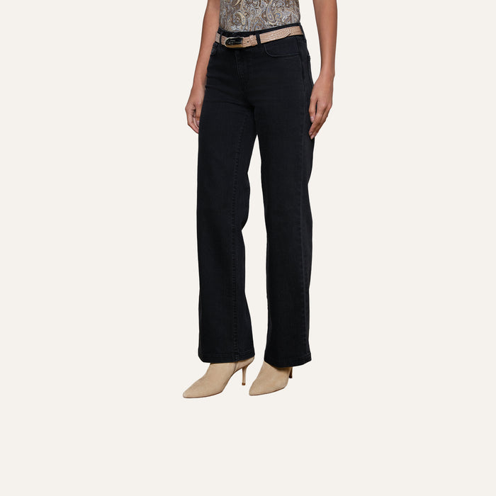 A person wearing the Scottie Wide-Leg Jean in black, featuring a high waist and contoured waistband, styled with a beige belt and beige pointed-toe heels, shown from shoulders to feet against a plain background.
