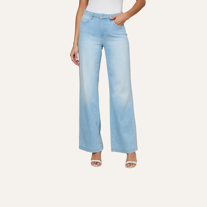 A woman, shown from the shoulders down, wears a white sleeveless top paired with the Scottie Wide-Leg Jean featuring a contoured waistband in light blue denim and high heels, standing against a plain background.