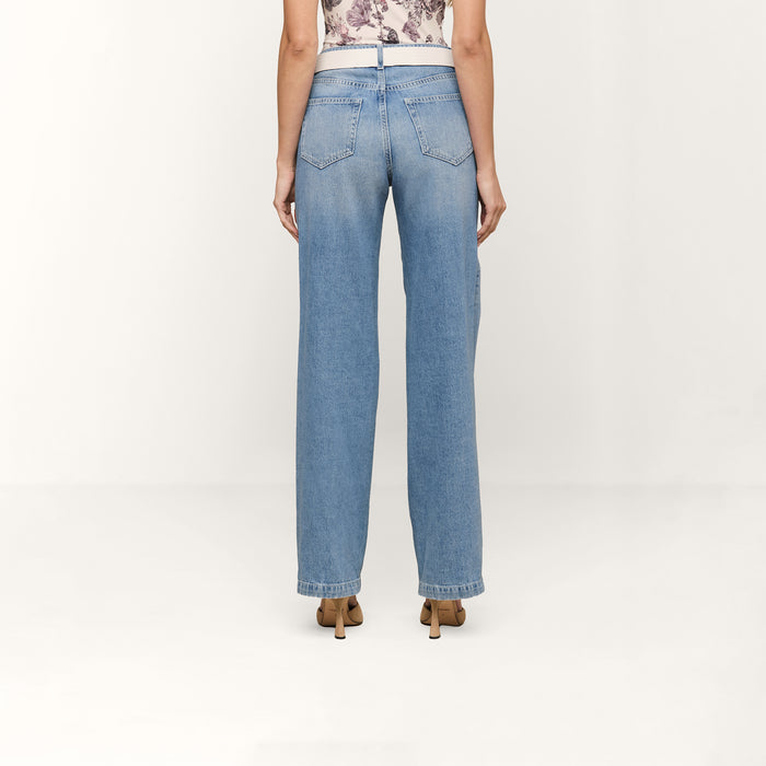 A person wearing the Scottie Wide-Leg Jean in light blue cotton denim and brown heeled shoes, viewed from the back against a plain white background.