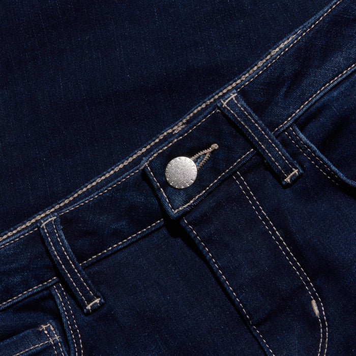 Close-up of the waistband and front pocket area of dark blue jeans with white stitching, silver button, and visible belt loops, set against a matching denim background.