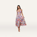 A woman stands against a plain white background wearing the Seina Poplin Midi Skirt, featuring a high-waisted, button-front design in a vibrant postcard print, paired with a matching sleeveless crop top.
