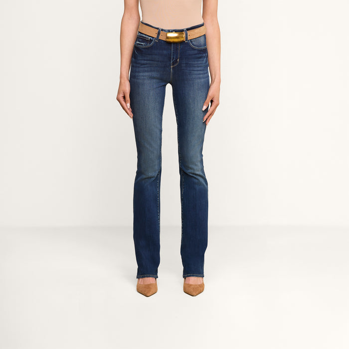 A person wearing the Selma Bootcut Jean styled with a brown belt and brown pointed-toe heels, posing against a plain white background. The image is cropped at the shoulders.