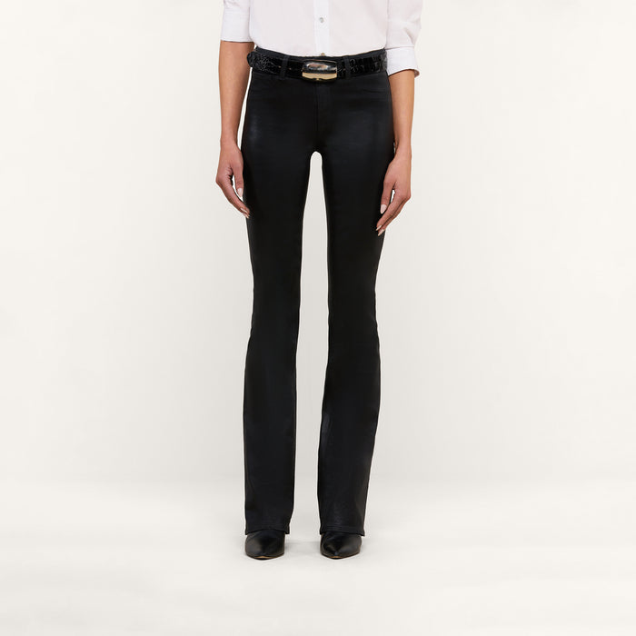 A person stands against a plain white background wearing the Selma Coated Bootcut Jean, styled with a white button-up shirt, a black belt, and black shoes. Their face is not visible.