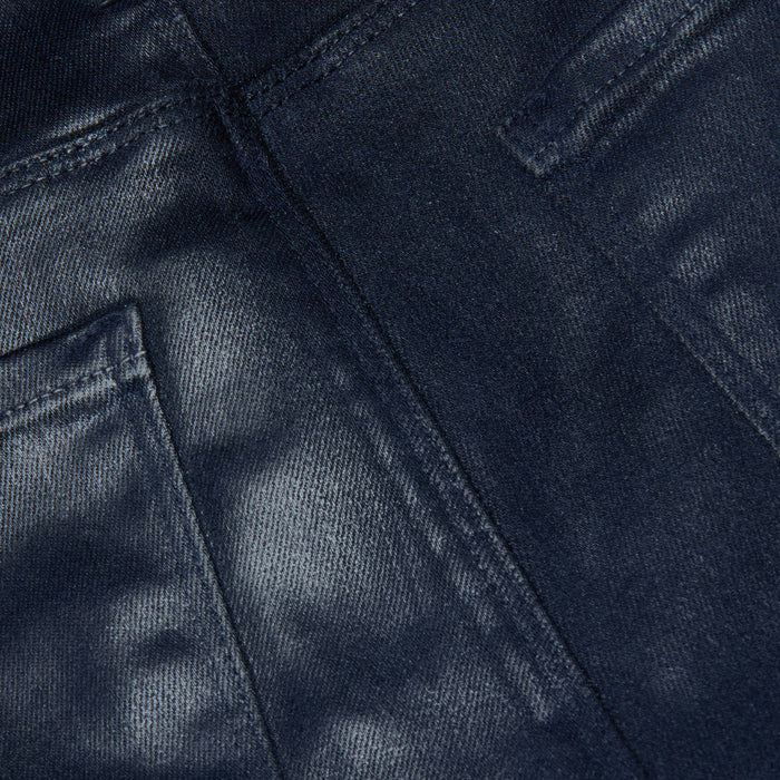 Close-up of the Selma Coated Bootcut Jean in dark blue, featuring detailed stitching and the edges of two back pockets, highlighting the texture and weave of its leather-alternative denim fabric.